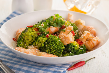Warm salad with grilled prawns, broccoli, fresh herbs, sesame seeds and chili peppers.