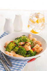Warm salad with grilled prawns, broccoli, fresh herbs, sesame seeds and chili peppers.
