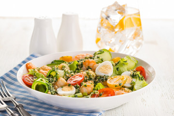 Salad with grilled shrimps, fresh lettuce, cucumbers, cherry tomatoes and quail eggs with pesto sauce.
