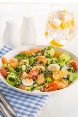 Salad with grilled shrimps, fresh lettuce, cucumbers, cherry tomatoes and quail eggs with pesto sauce.