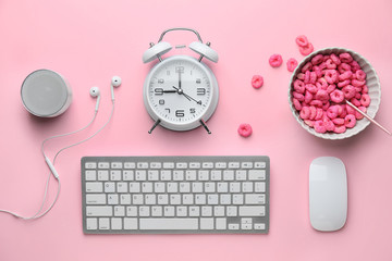 Computer keyboard with mouse, alarm clock and cornflakes on pink background
