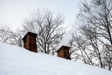 White smoke comes out of a house's chimney,  winter day