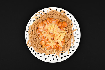 Spaghetti with cheese and meat watered with sauce on a black background.