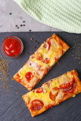 Pizza with tomatoes, cheese and tomato ketchup on a stone flat board on a gray background