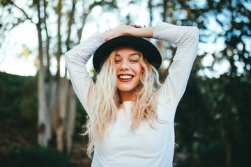 Chica felíz rubia con sombrero con fondo natural verde.