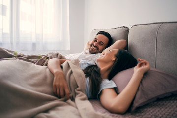 Obraz premium Young happy couple is lying in bed in the morning.