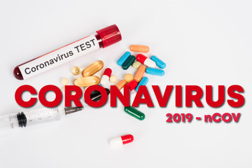 Obraz premium colorful pills near sample with coronavirus test, syringe and coronavirus 2019-ncov lettering on white