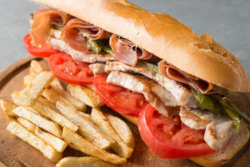 Sandwich Serranito typical in Andalusia with ham, green pepper and grilled pork loin