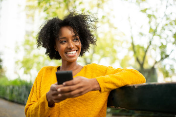 Close up attractive young woman sitting outside with mobile phone