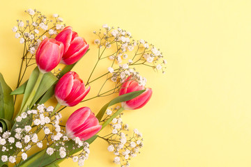 Bouquet of tulips and gypsophila on a yellow background.