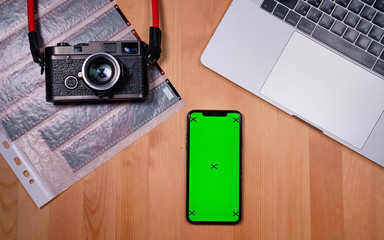 smartphone on a desktop background with a book and a film camera work with a mobile phone, scrolling applications