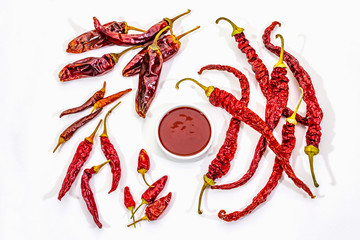 Spicy chili sauce in bowl isolated on white background. Different varieties of dry hot peppers, main ingredient for preparation. Cooking backdrop, mockup