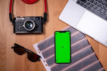 smartphone on a desktop background with a book and a film camera work with a mobile phone, scrolling applications