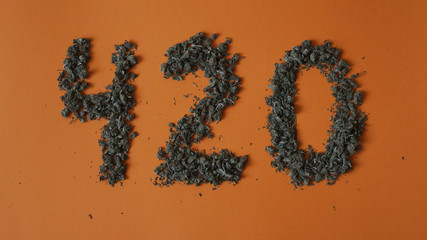 Top view close up sign 420 made from a hemp buds on red background