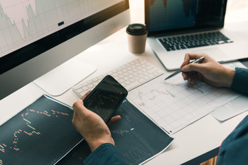 Investors use smartphones view investment graphs and record statistics on stock performance results...