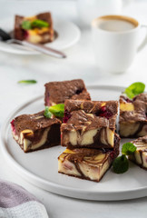Cheesecake brownies with raspberry stacked on a white plate.