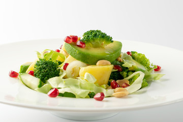 Green Salad with Avocado, Cucumber and Nuts on White Plate
