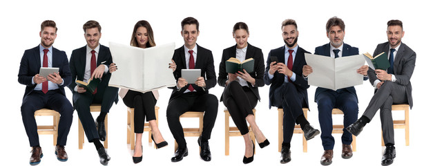 8 businessmen reading from tablet, phone, book and newspaper