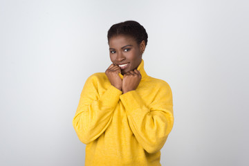 Beautiful African American woman looking at camera. Attractive smiling young lady holding turtleneck collar. Female beauty concept