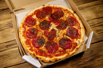 Delicious fresh pizza in cardboard box on a wooden table. Concept for home delivery of food, fast food, delivery of pizza