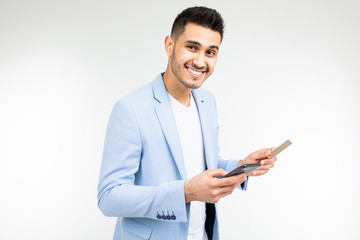 a man enters data with a credit card into a mobile phone to make a purchase via the Internet on a white background