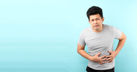  handsome of asian man Sick has stomachache isolated on blue background in studio With copy space.
