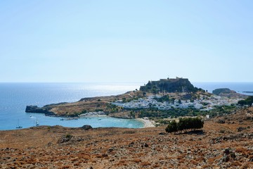 Fototapeta na wymiar Lindos, Rhodes, Greece. Overview of Lindos. Spectacular view to the beach, Lindos village and the Acropolis of Lindos with temple of Athena Lindia