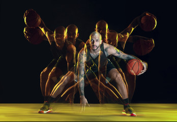 Young basketball player of team in sportwear training, practicing in action, motion isolated on...
