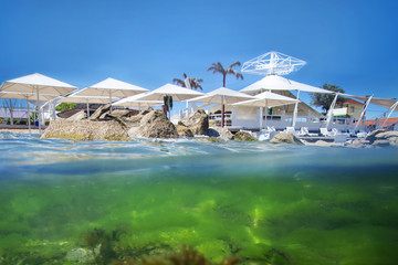 Exotic beach, half under water on the background of the uncovered sun umbrellas