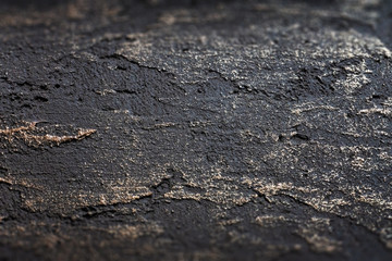 Black and gold facade plaster wall texture. Stone decorative plaster or concrete wall abstract background with selective focus. Decorative plaster inside the house.