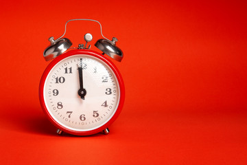 red classic alarm clock on a red background in the studio