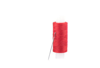 Close-up photo of a spool with red thread and a needle isolated over white background.