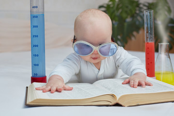 Education and home training. Cute baby reads a book on medicine, science, chemical experiments....