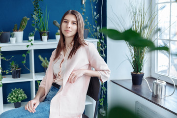 A girl in a pink sweater and jeans sits on a chair in the abortion floor. In the background are...