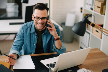 Businessman in office. Handsome man talking on phone at work.