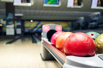 multi-colored bowling balls lie on shelf in bowling club