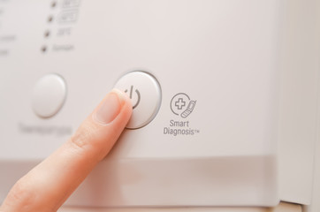 woman's finger presses the button to turn on the washing machine close up