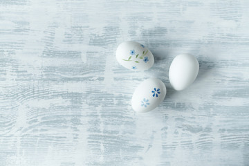 Fototapeta na wymiar White Easter eggs with blue flowers on painted wooden background. Copy space