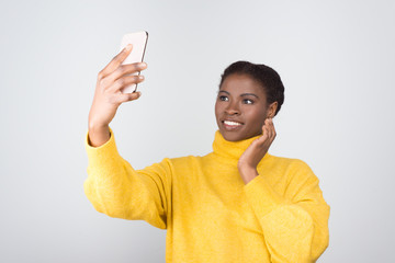 Beautiful African American woman taking selfie with smartphone. Attractive young lady posing for...