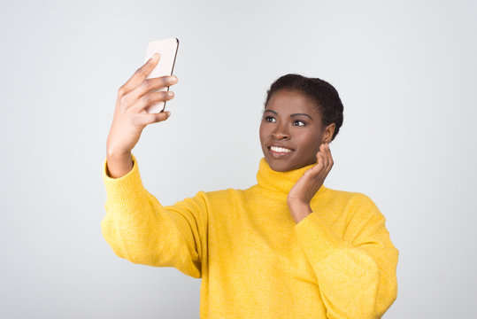 Beautiful African American woman taking selfie with smartphone. Attractive young lady posing for self portrait. Self portrait concept