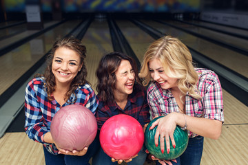 Fototapeta na wymiar three happy girls posing with bowling balls in club