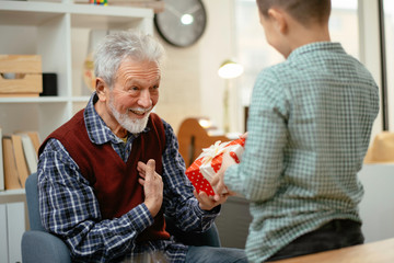Grandfather giving gift to grandson. 
