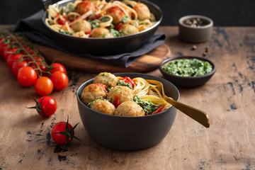 Pasta with meatballs and spinach with tomato sauce.