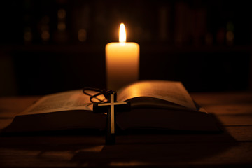 bible is lying open on a table and a candle is burning