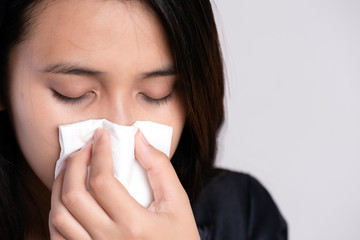 Close up young asian woman got sick, flu and nose allergy sneezing in a tissue. Healthcare and...
