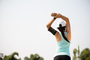 Young fitness woman runner stretching arm before run in the park. Outdoor exercise activities...