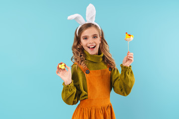 Photo of joyful blonde girl holding colorful eggs and toy chicken
