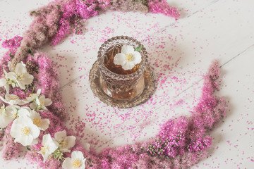 Flowers composition. circle made of pink flowers with a glass of tea on a white background. Top view, flat lay.