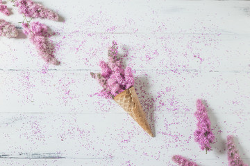 waffle cone with a pink flowers on a white background. Creative design for pastel wallpaper. Top view, flat lay.