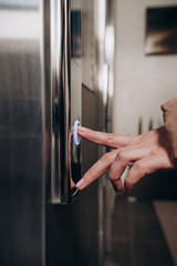 a woman in a jacket presses the button to call the Elevator